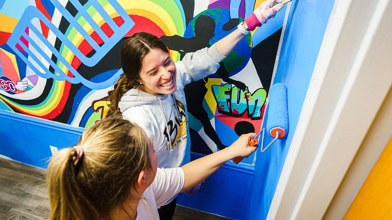 Students volunteer by painting a mural