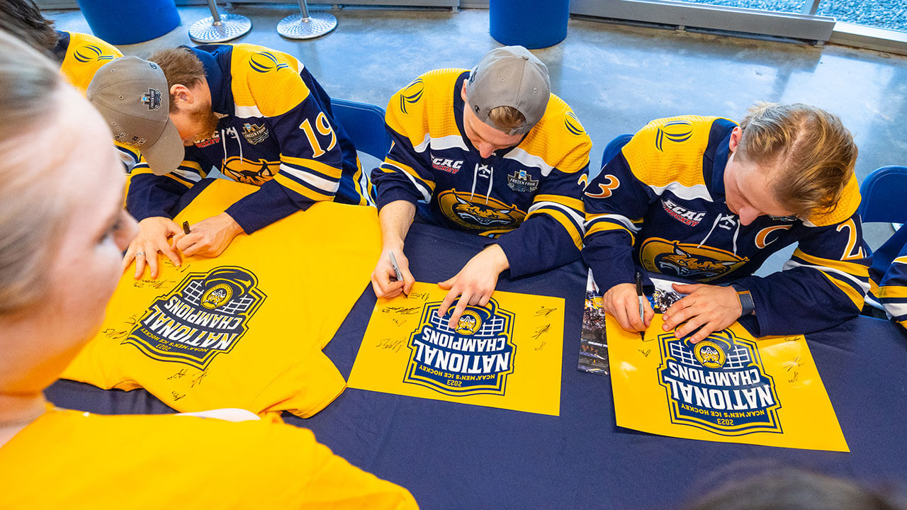 Quinnipiac hockey players sign Frozen Four merchandise