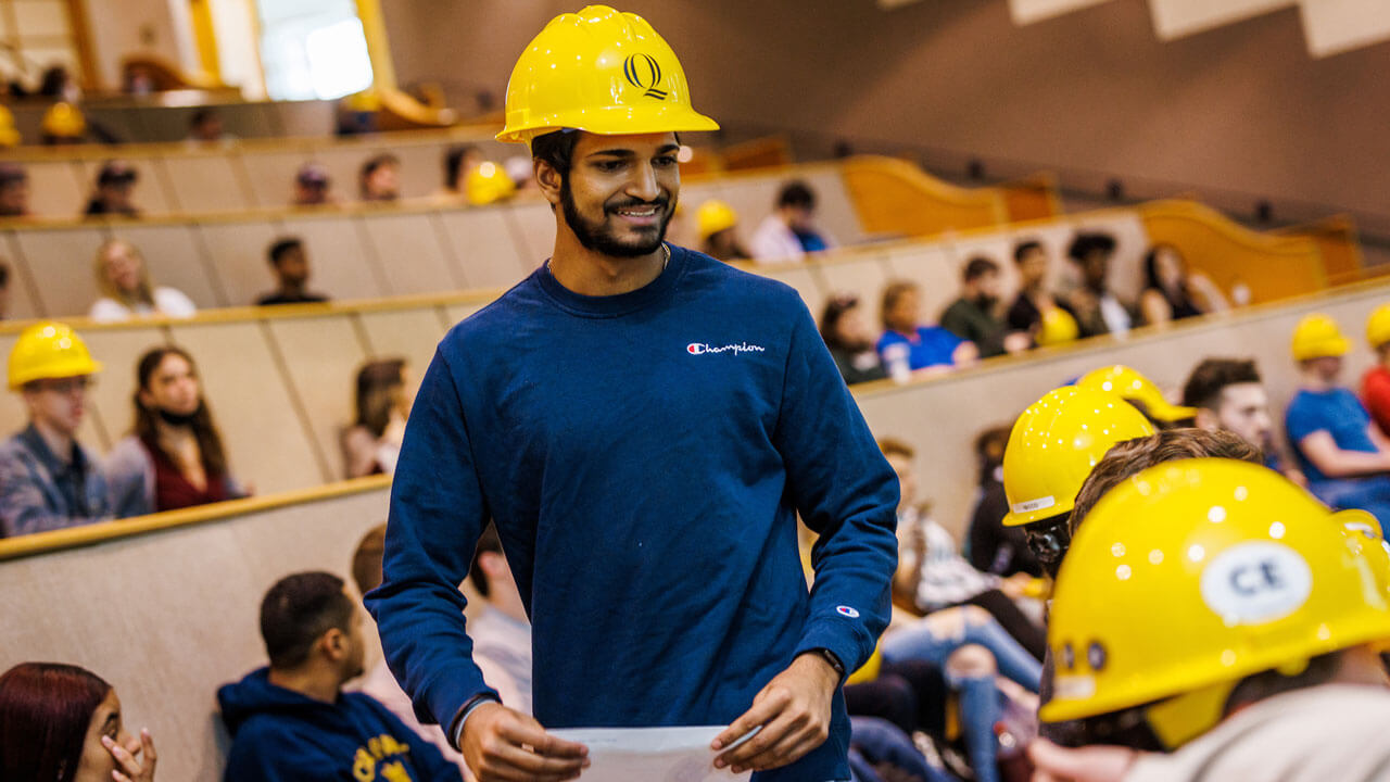 Student smiles at hard hat ceremony while standing in the crowd