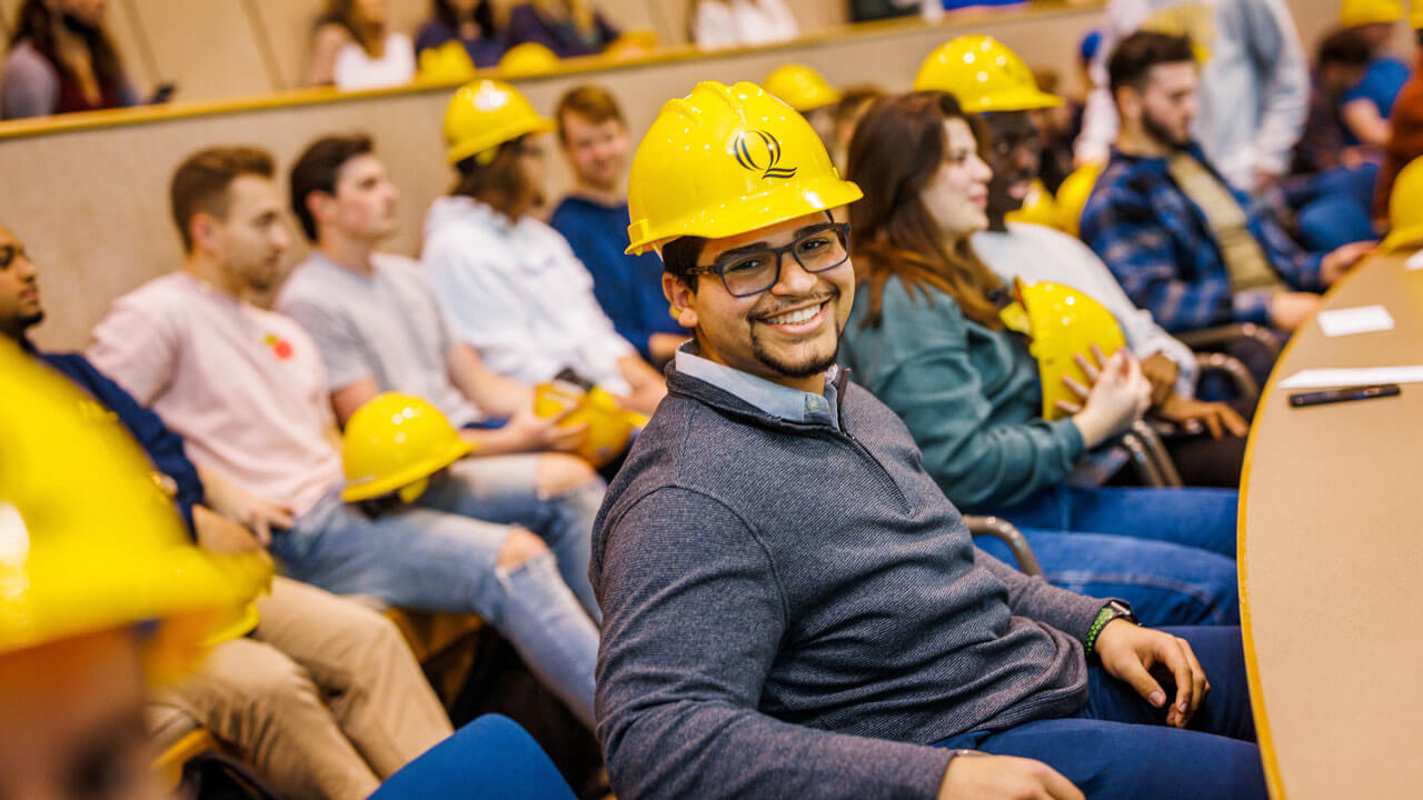 student smiling at camera while wearing hard hat at hard hat ceremony