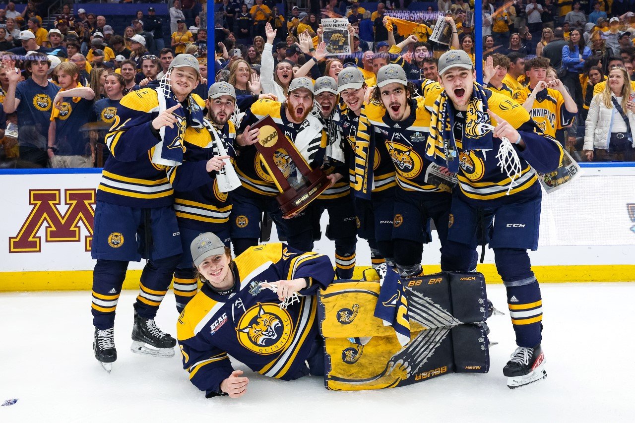 Men's ice hockey players hold the NCAA Championship trophy and cheer