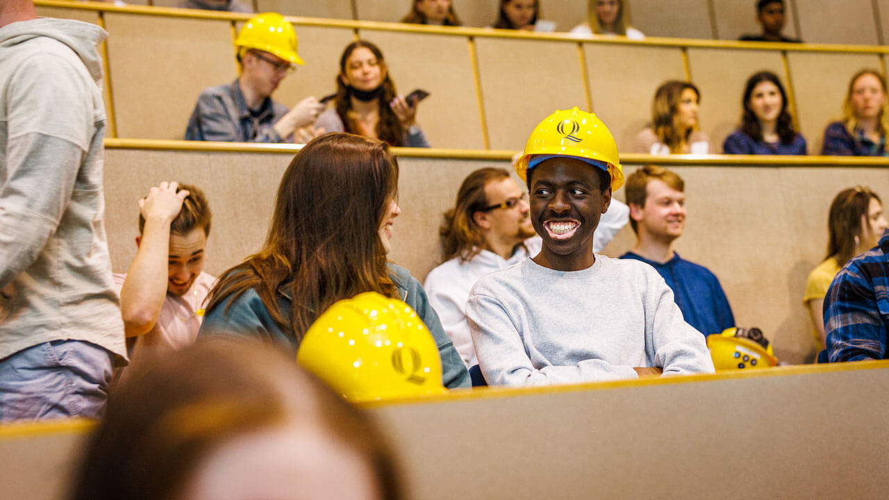 Students smiling at each other in the crowd while wearing their hard hats at hard hat ceremony
