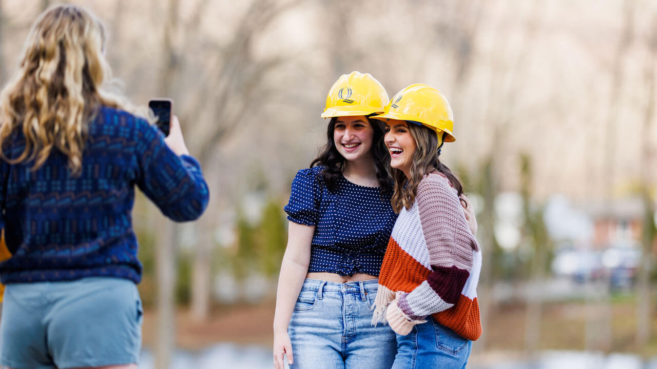 Two female engineer students smiling and posing while taking picture outside by cce