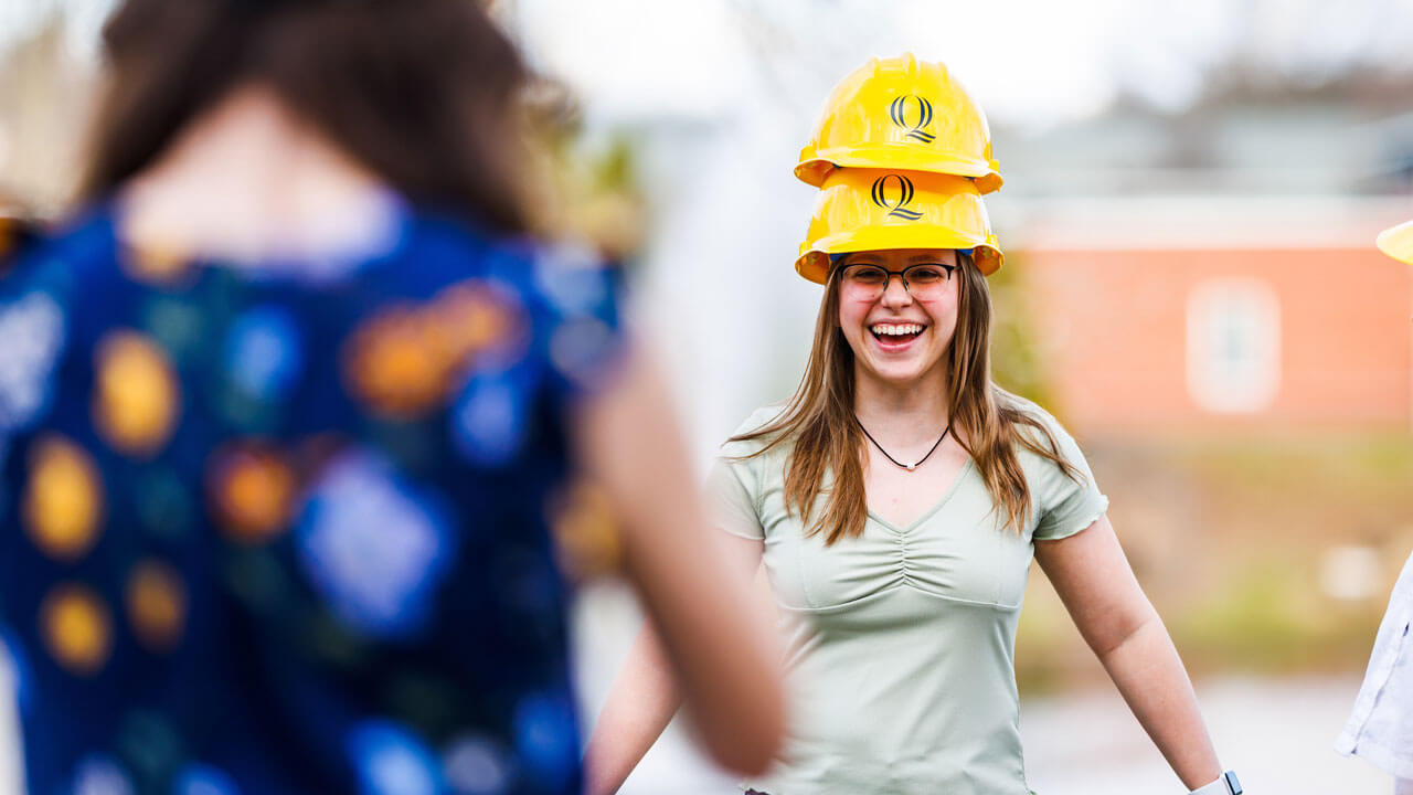 Girl wears two hard hats and laughing while taking picture outside CCE