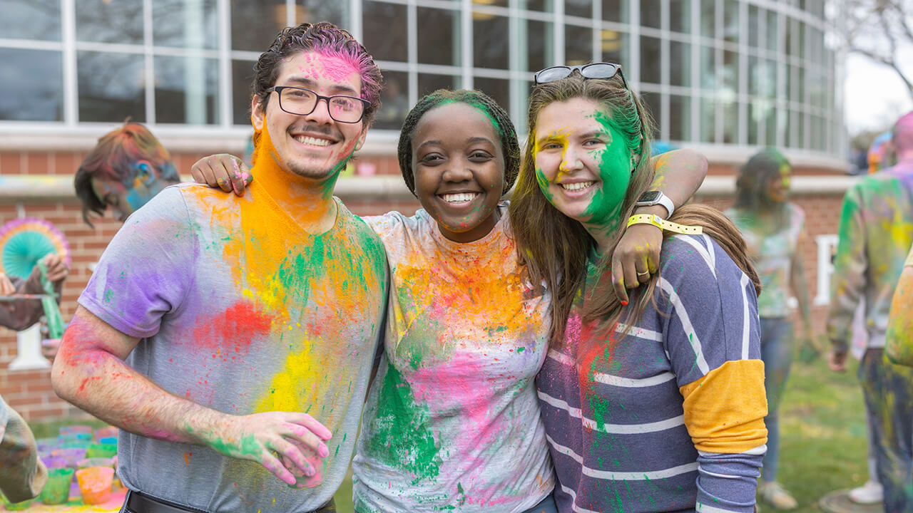 Group of students smiling together for picture at Holi celebration