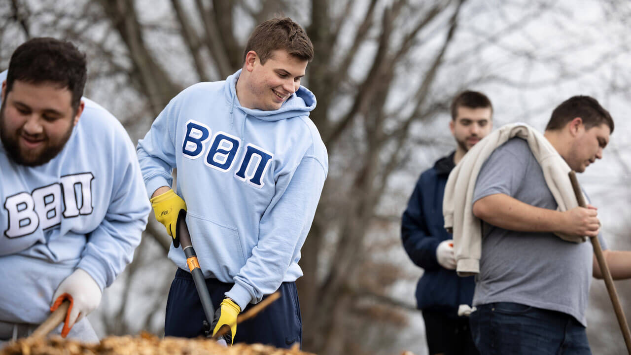 Frat brothers help each other garden and shovel at the Big Event