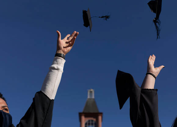Graduates throw their commencement caps in the air in celebration