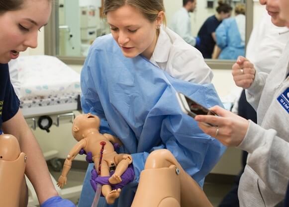Students help deliver a baby during a simulated birth in the Center for Medicine, Nursing and Health Sciences