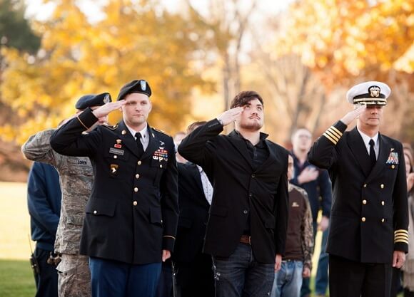 Quinnipiac student veterans, from left, sophomore Alex Hartman, a game design major, and freshman Michael Thompson, a political science and legal studies major, and Jason Burke, director of veteran and military affairs at Quinnipiac, salute during the National Anthem at the Veterans Day flag raising ceremony on the North Haven Campus.