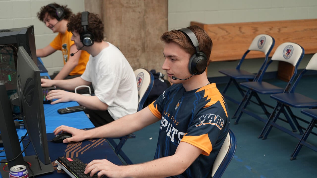 Quinnipiac Esports member sitting at computer with teammates