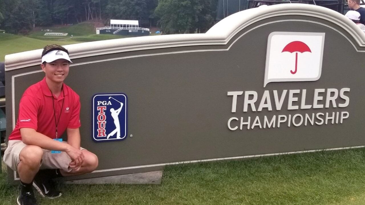 Burnham smiles in front of the Travelers Championship sign