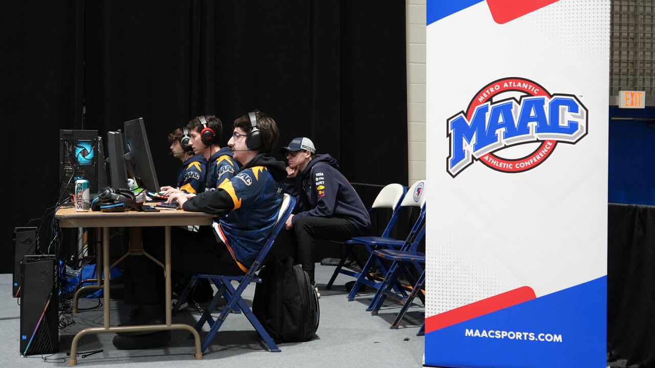 Quinnipiac Esports members competing next to the MAAC Esports banner