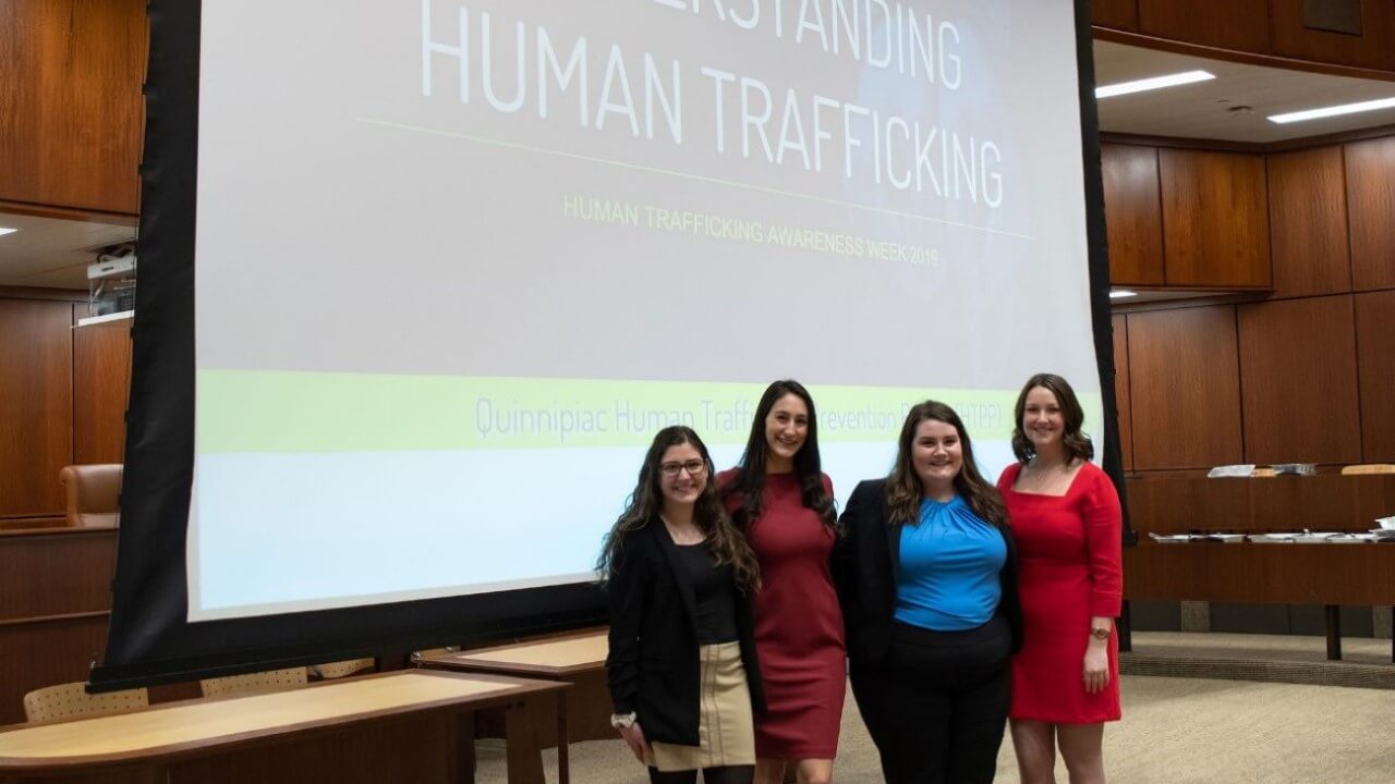 Four women in front of a screen that reads Understanding Human Trafficking