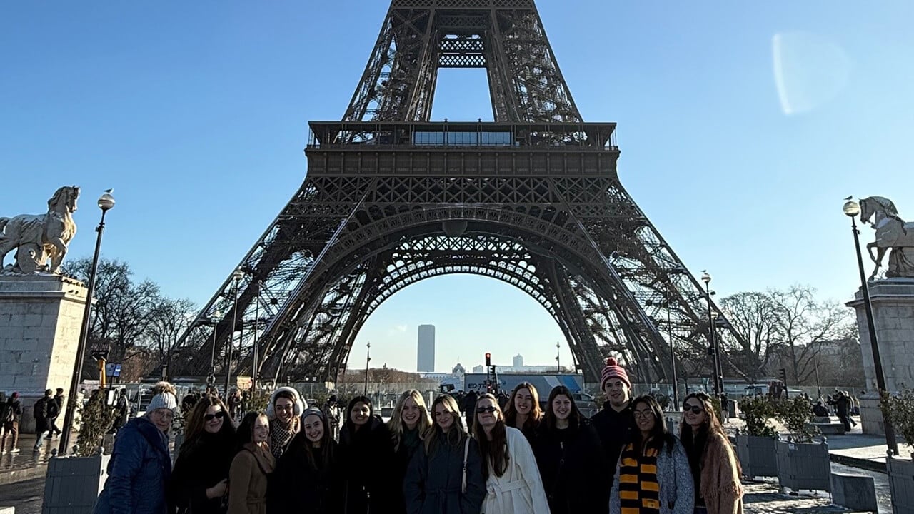 Study abroad trip gathered at the bottom of the Eiffel Tower