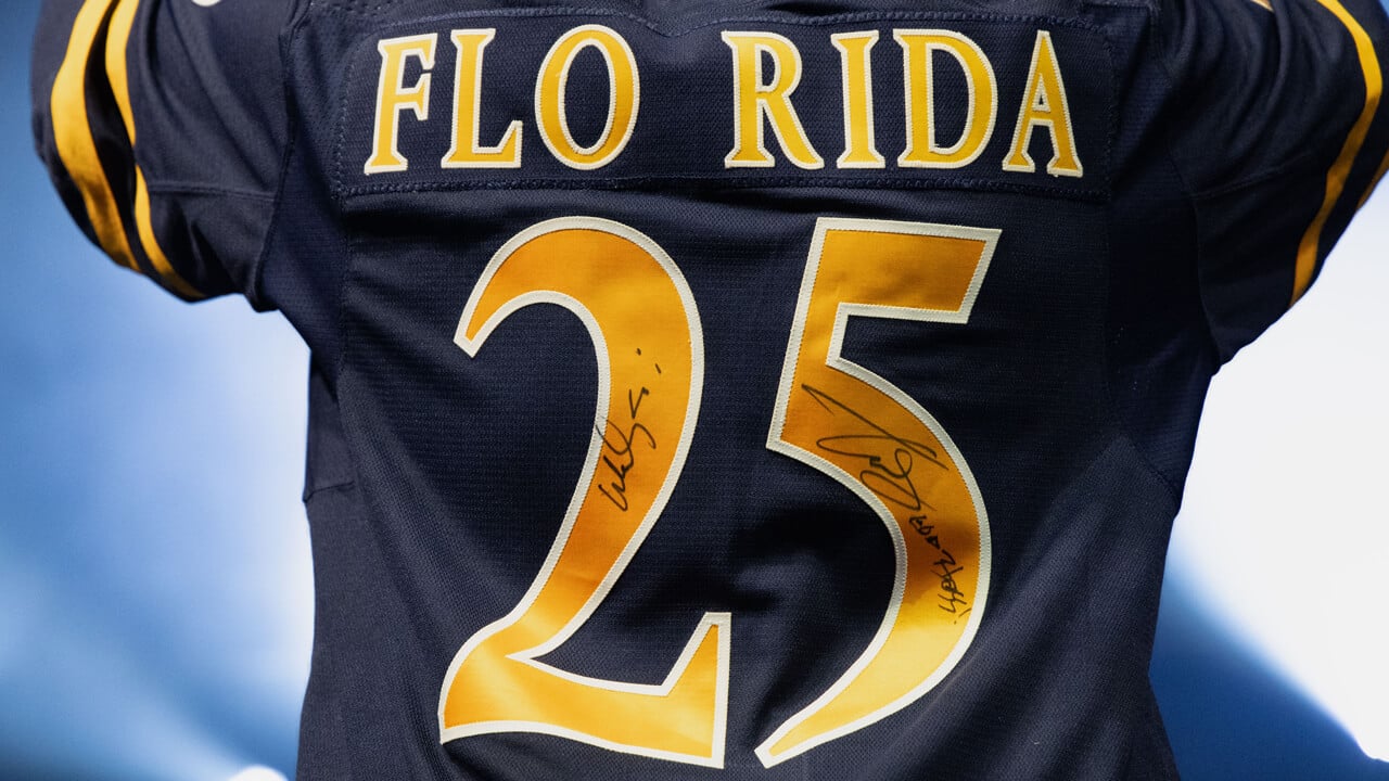 Flo Rida shows his custom jersey on stage reading "Flo Rida"