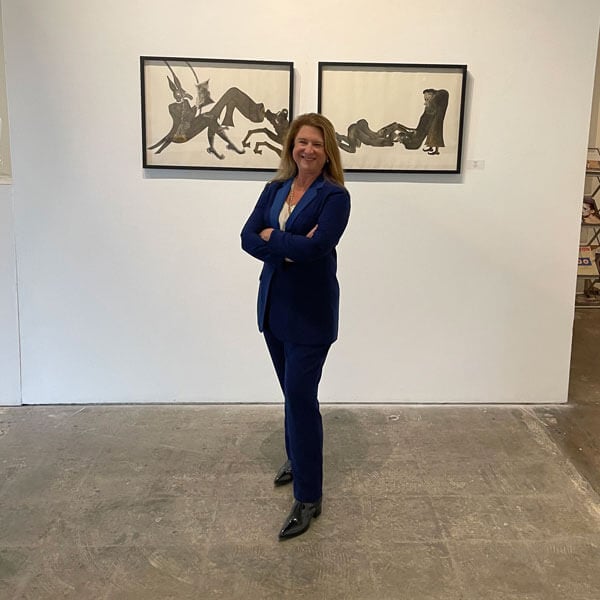 Deborah Colton standing in front of paintings