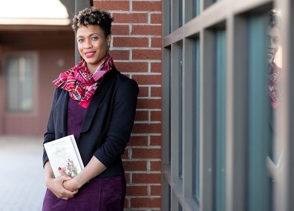 Professor Sasha Turner stands outside Quinnipiac's College of Arts and Sciences holding her book in her hands.