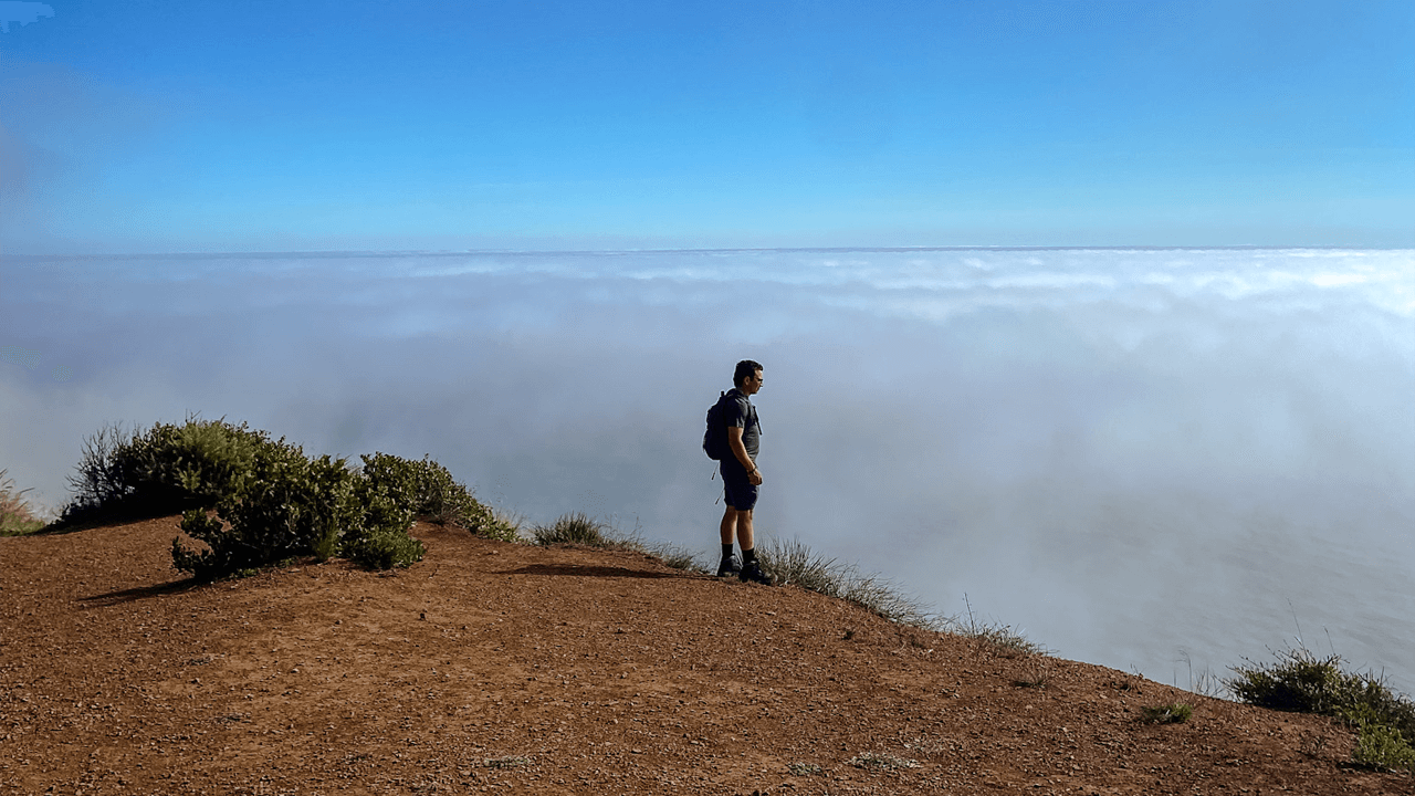 Man looks over cliff with clouds in Malibu