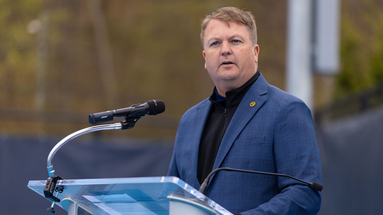 Speaker standing at the podium at the Peter Liberti Tennis Complex ceremony