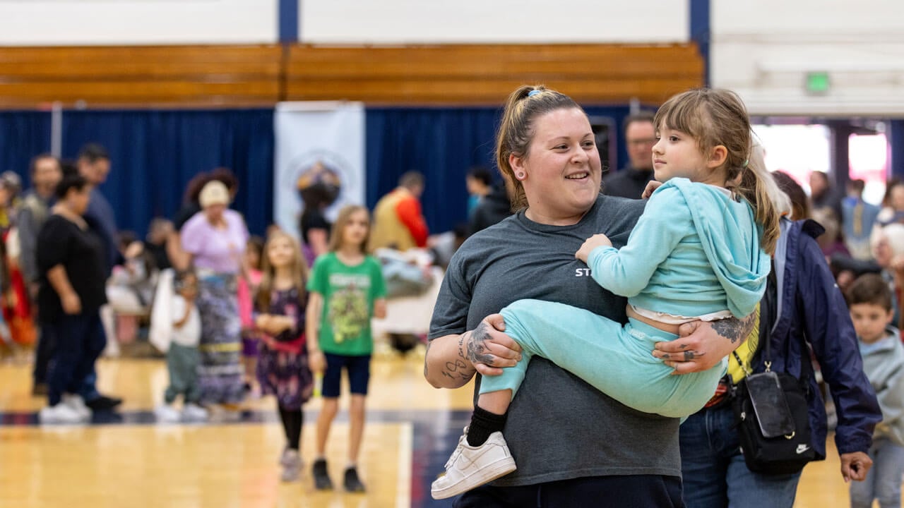 A mother and her child watch the performers dance at the Dancing in the Shadow of Sleeping Giant Powwow on Quinnipiac’s campus