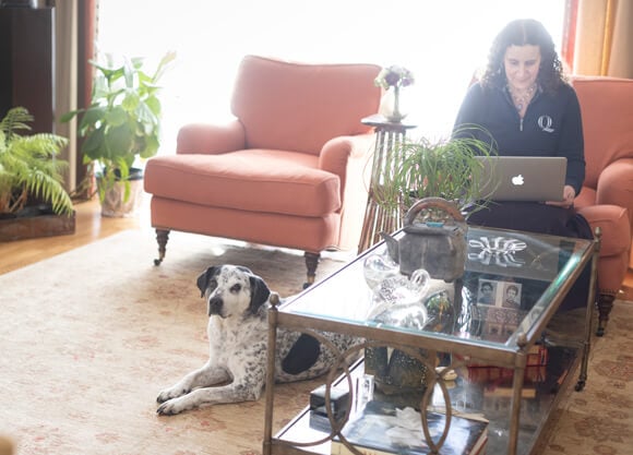 Student working in a home environment with her dog.