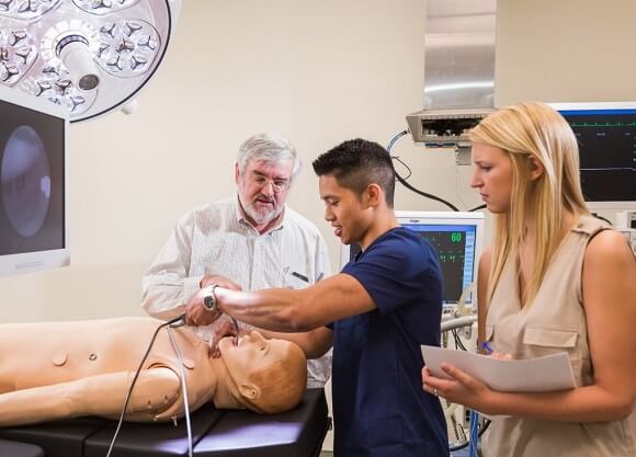 Students examine a simulated patient.