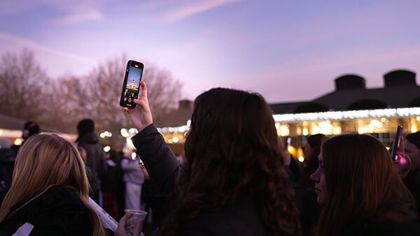 Student taking photo of the Arnold Bernhard Library during the annual Quad lighting