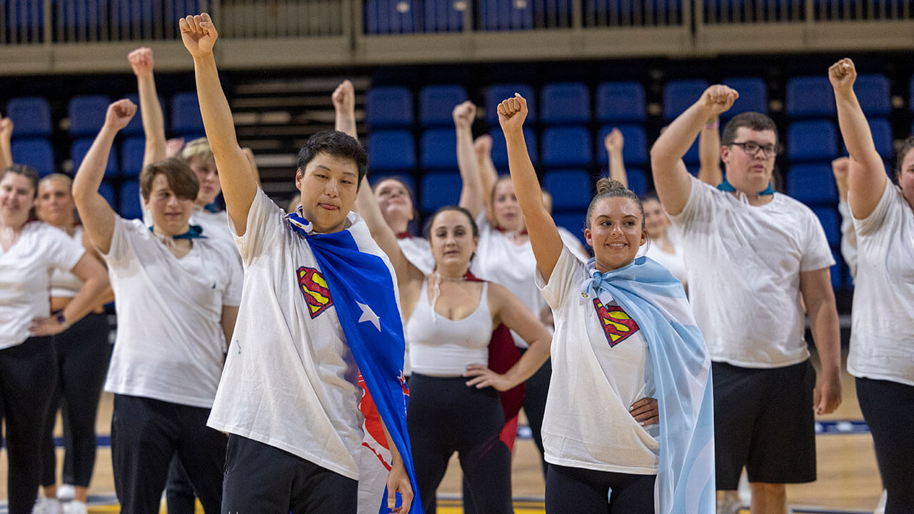 Students dressed as Superman dance together in a Greek Week dance competition