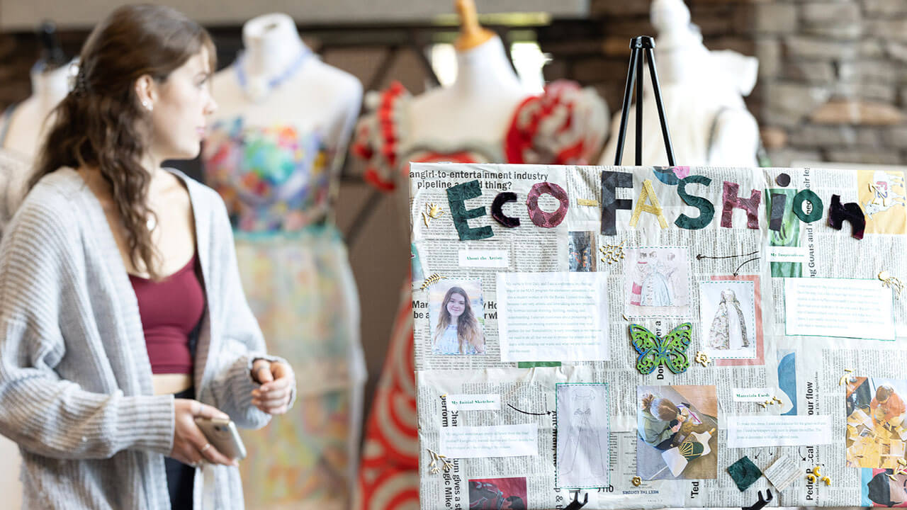 Students recycled dresses are displayed next to an eco-fashion sign