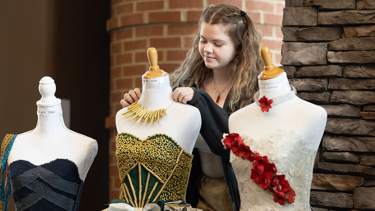 Students touch up their sustainable dresses made from recycled items