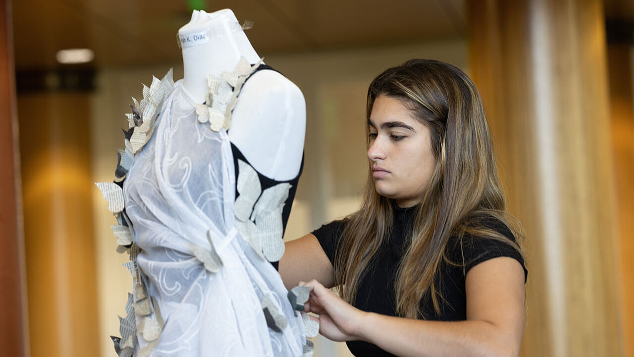 A student places her eco-fashion piece on a manikin