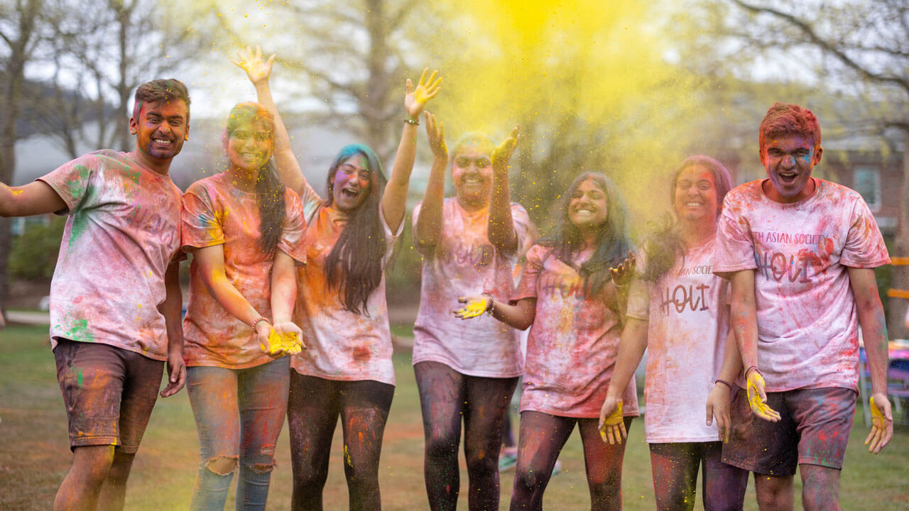 A group of students throw colored powder at Holi celebration