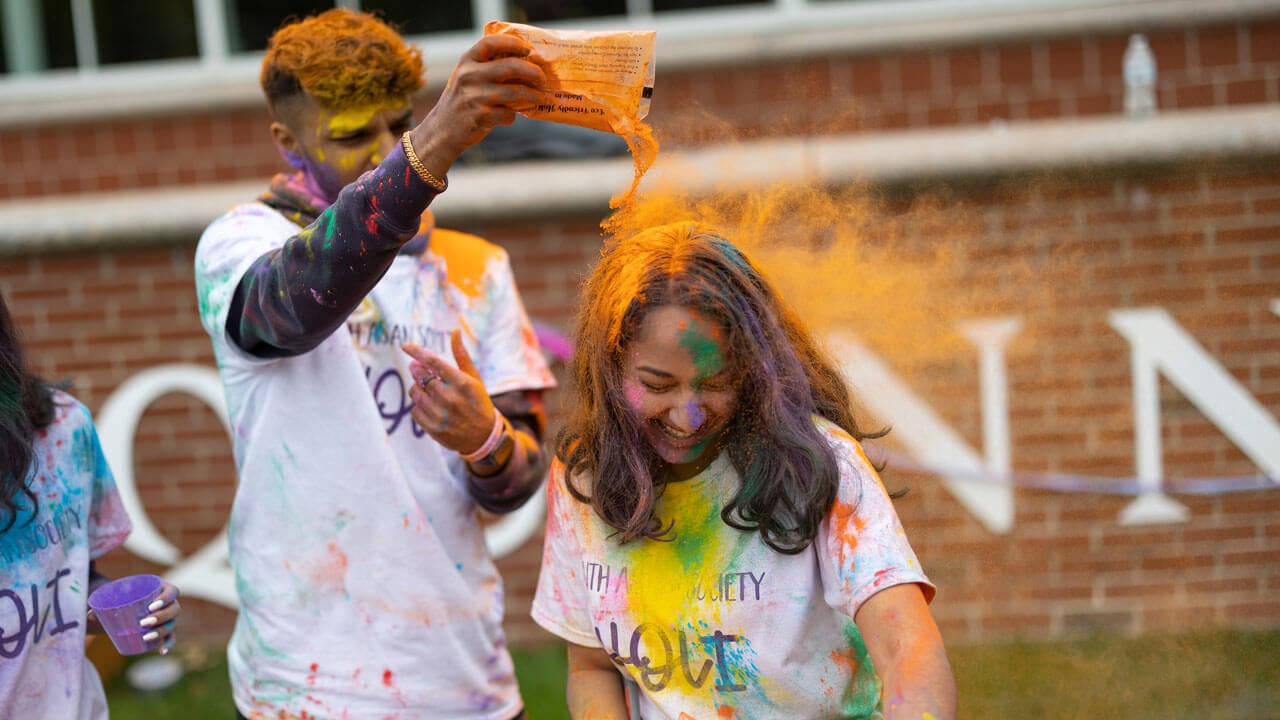 A student getting orange powder poured on her head