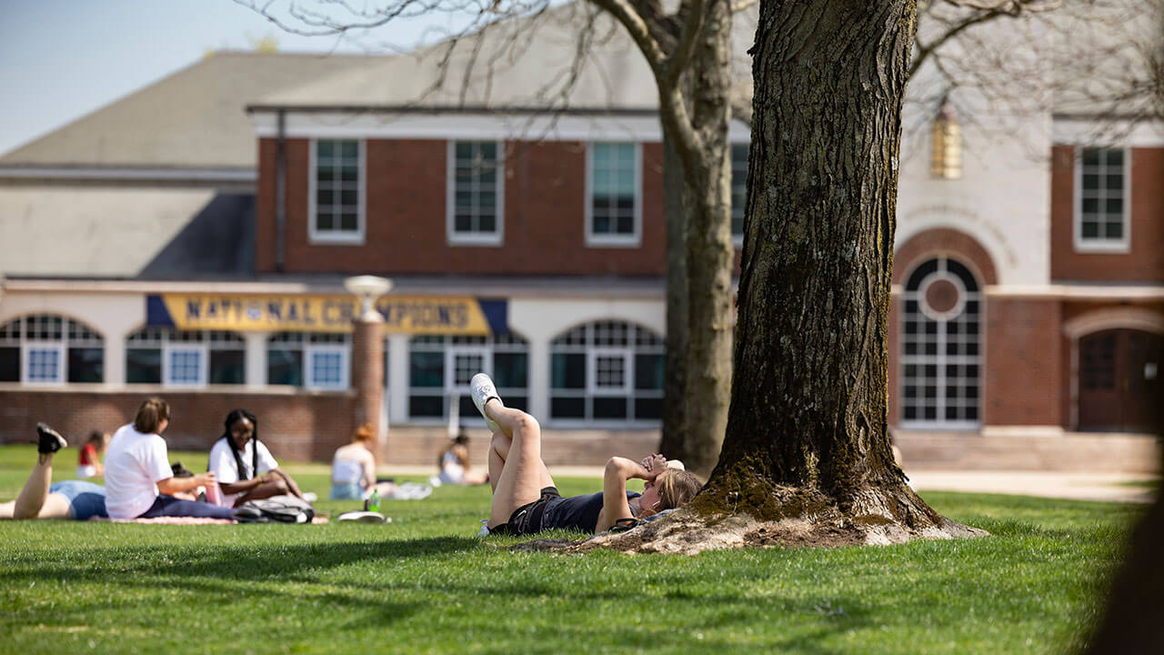 Student lounges on the Quad and soaks up the sun