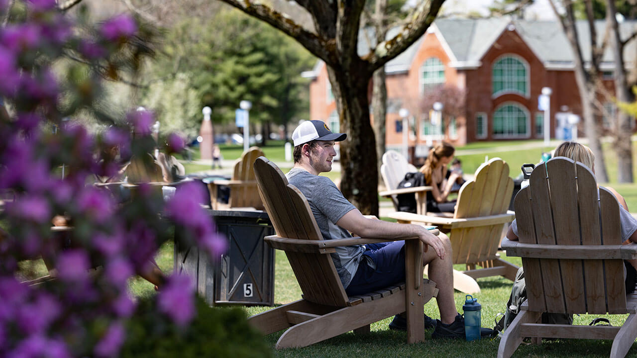 Student relaxes on a lounge chair on the Quad on a warm day