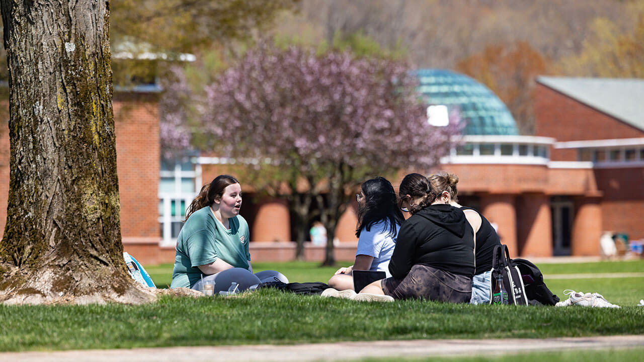 A group of students sit on the Quad and enjoy the Spring weather