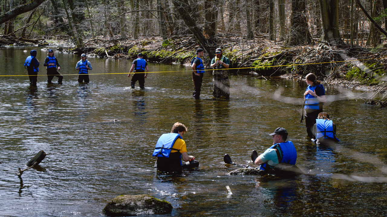 Civil engineering students measure streamflow with the USGS at the Mill River.