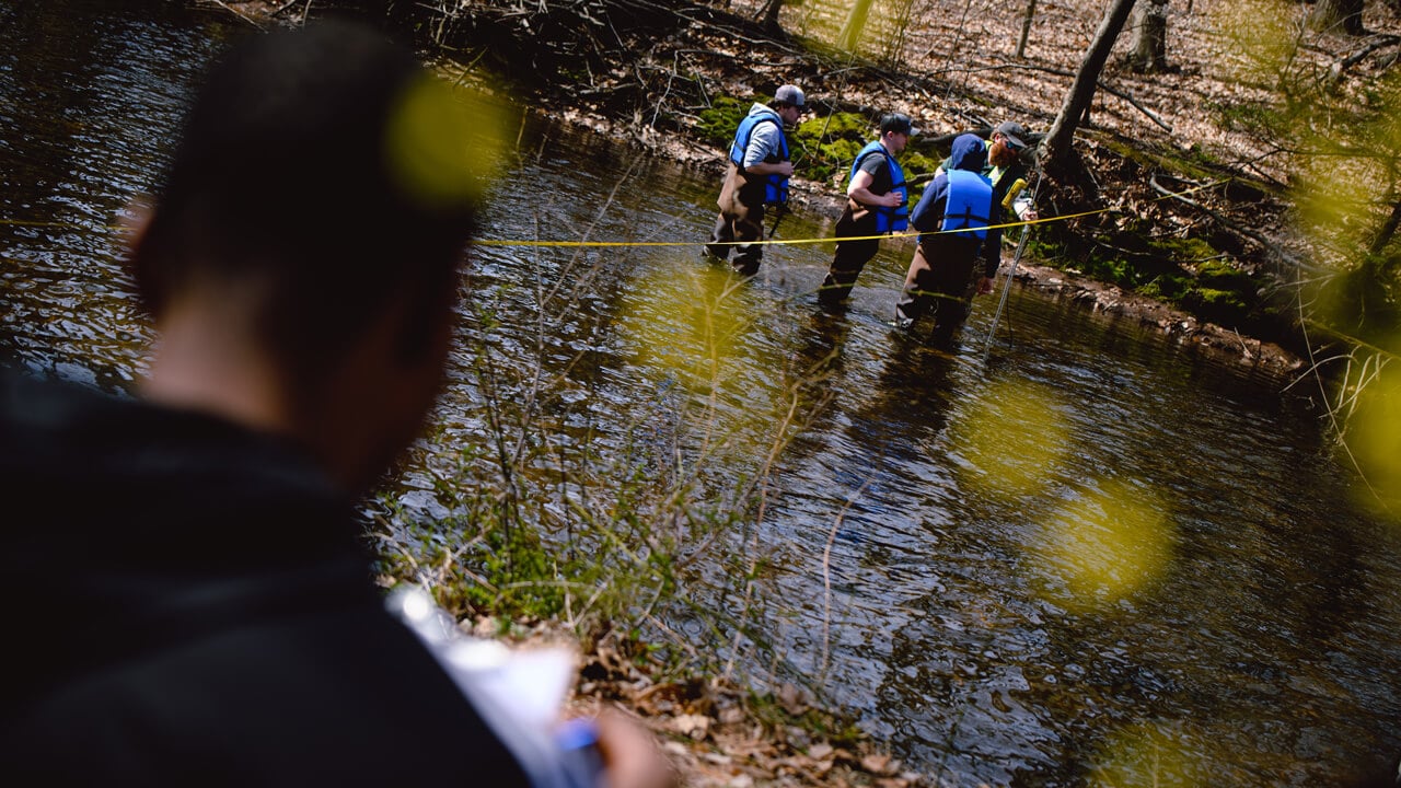 Civil engineering students measure streamflow with the USGS at the Mill River.