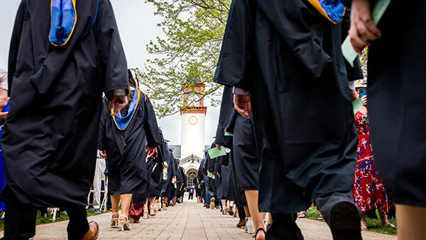 Quinnipiac graduates walk through the Mount Carmel Campus Quad during a Commencement ceremony.