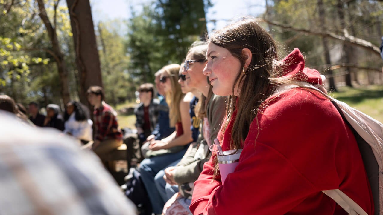 Students listen to their professor speak as part of an outdoor classroom