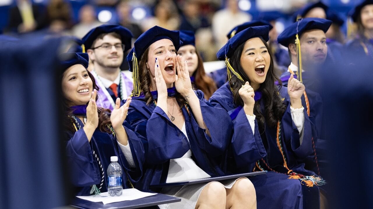 Graduates cheer and clap together during ceremony