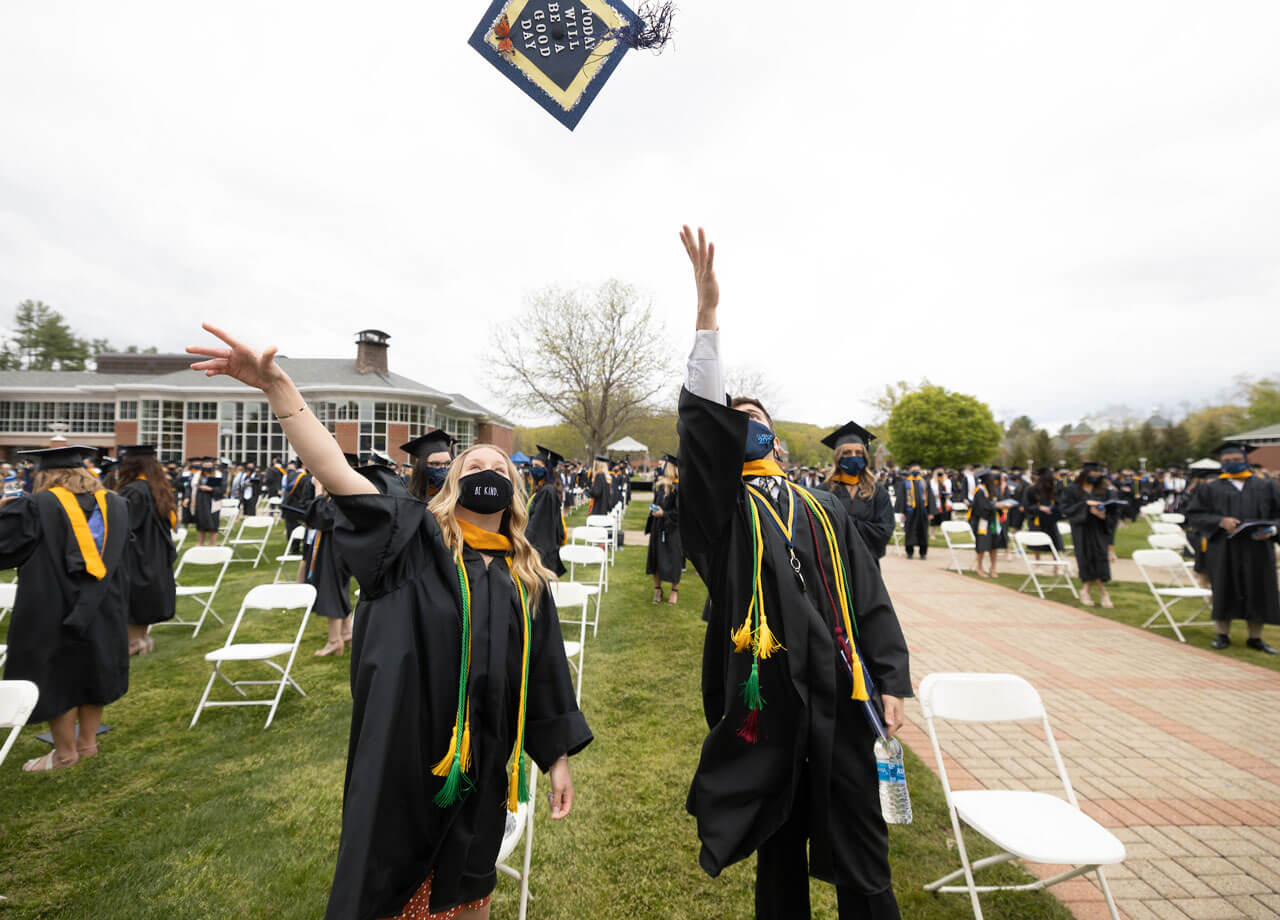 Graduates of the Class of 2021 throw their caps in the air in celebration