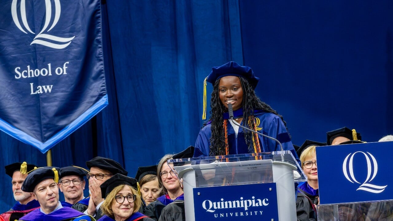 Student speaker standing at the podium and smiling at graduates