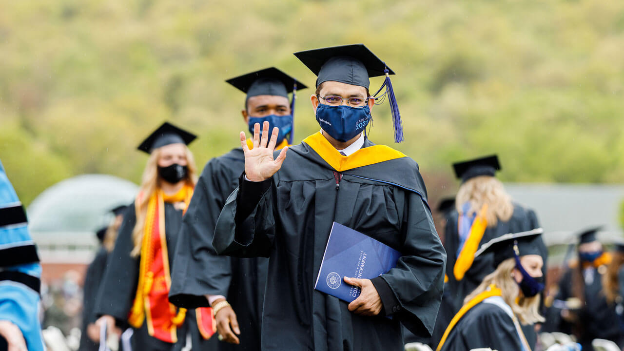 Student waving while holding his diploma