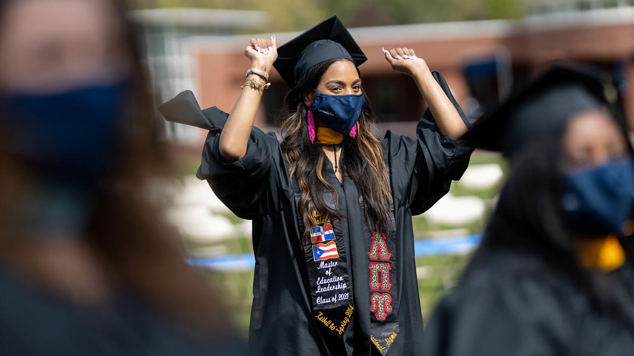 A graduate pumps her fists in the air in celebration