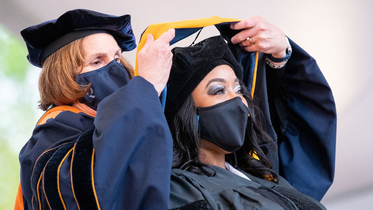 A graduate receives her doctoral hood during Commencement
