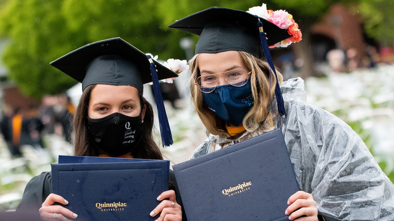 Two rain-soaked graduates pose for a photo