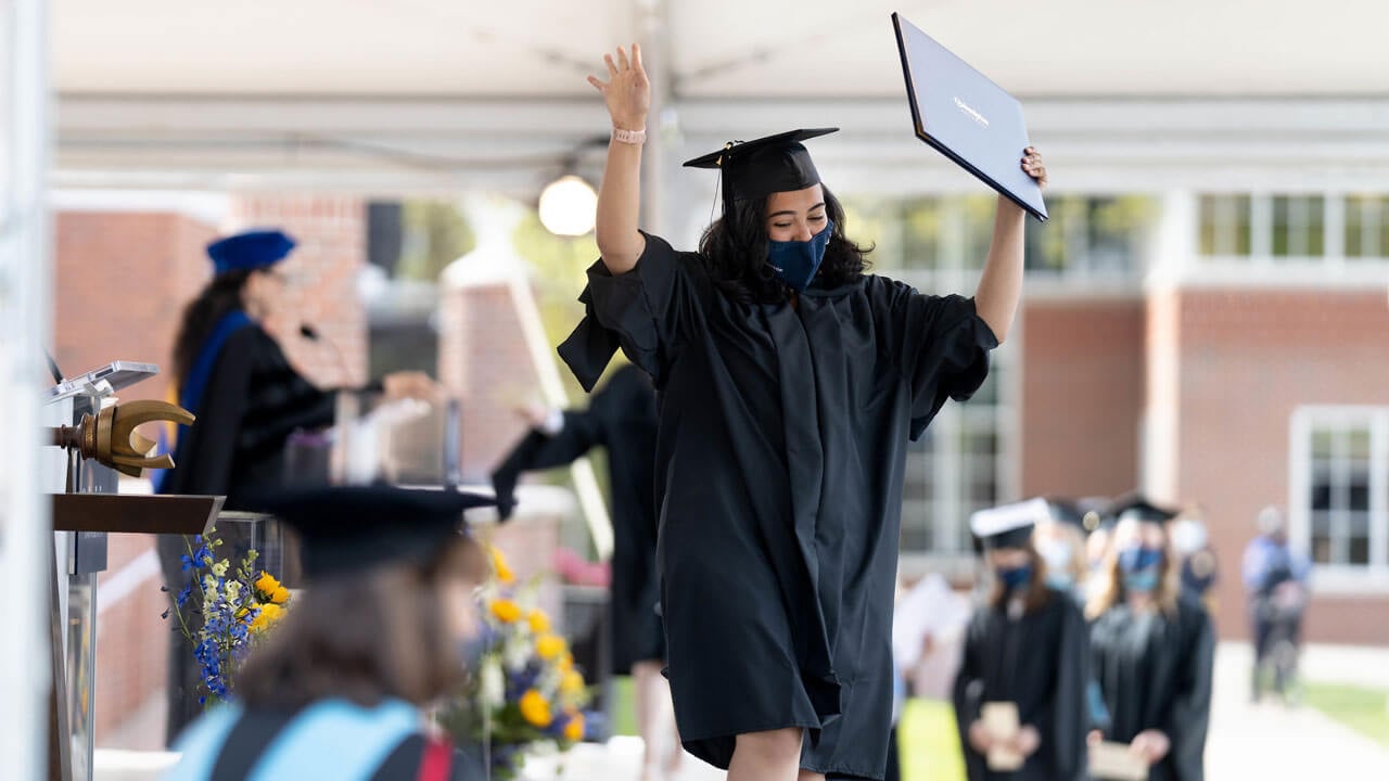 A graduate celebrates her Commencement while walking across the stage