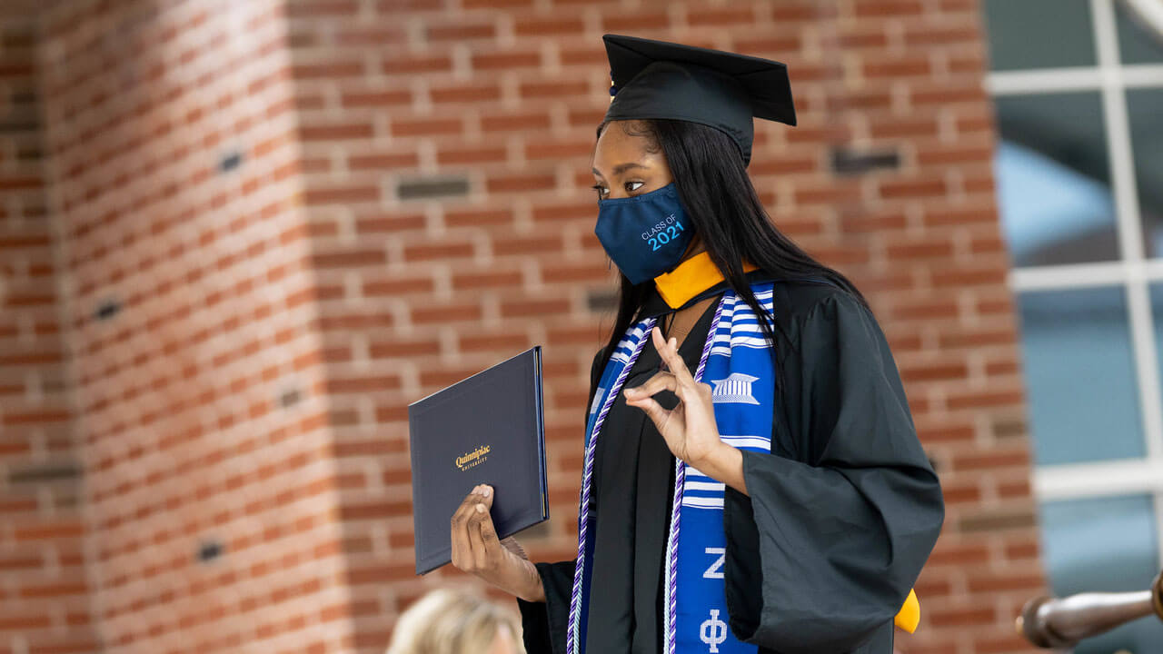 A graduate poses for a photo as she crosses the stage during Commencement