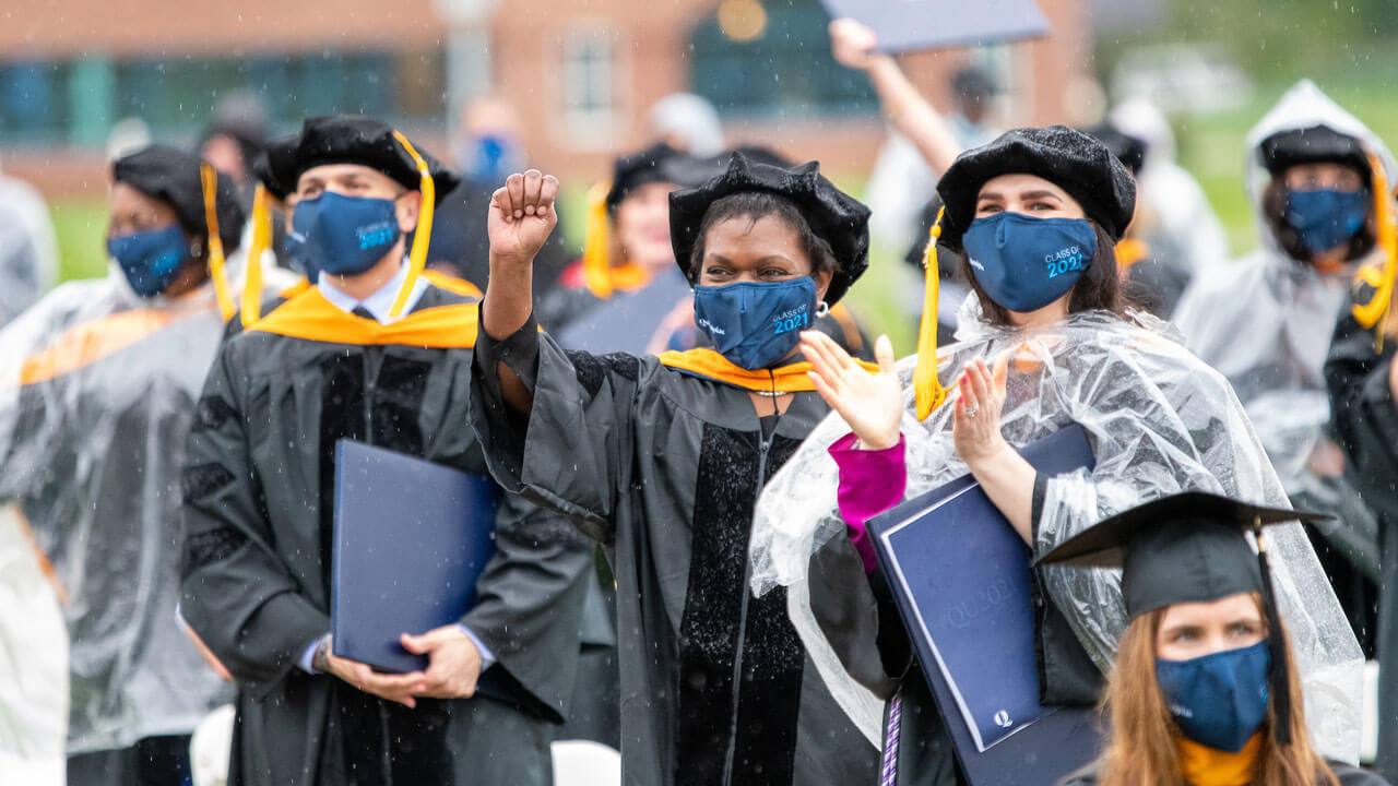 Three rain-soaked graduates celebrate their accomplishments